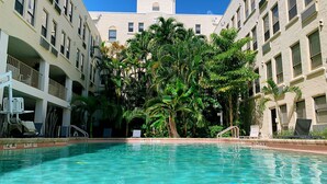 Una piscina rodeada de edificios con balcones y palmeras.