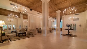 Un hall espacioso con techos altos, candelabros y una zona de estar central con sofás y una mesa de centro.