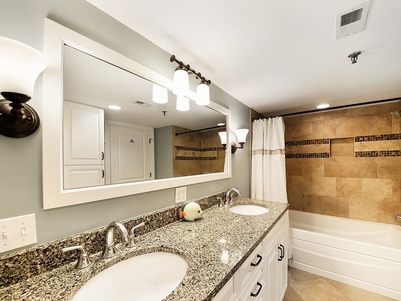 A bathroom with two sinks, a large mirror, and a shower area.