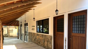 A corridor with stone walls, wooden doors, and hanging lanterns.