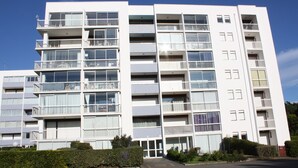 A multi-story residential building with balconies, a parking lot, and a clear sky. - "All Baigne" - 1CH apartment with loggia closed sea panorama (Quiberon)