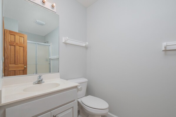 A bathroom with a white sink, mirror, and toilet.