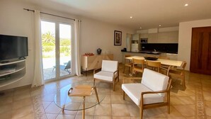 Ein modernes Wohnzimmer mit Fernseher, Sitzecke und einer Küche im Hintergrund.