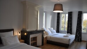 Une chambre d’hôtel avec deux lits, une table d’appoint en marbre, une table de chevet et une grande fenêtre avec des rideaux.