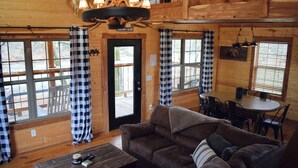 A cozy cabin interior with a wooden dining table, a sofa, and a coffee table. - Majestic Moose Lodge- Oark Cabin Rentals (Oark)