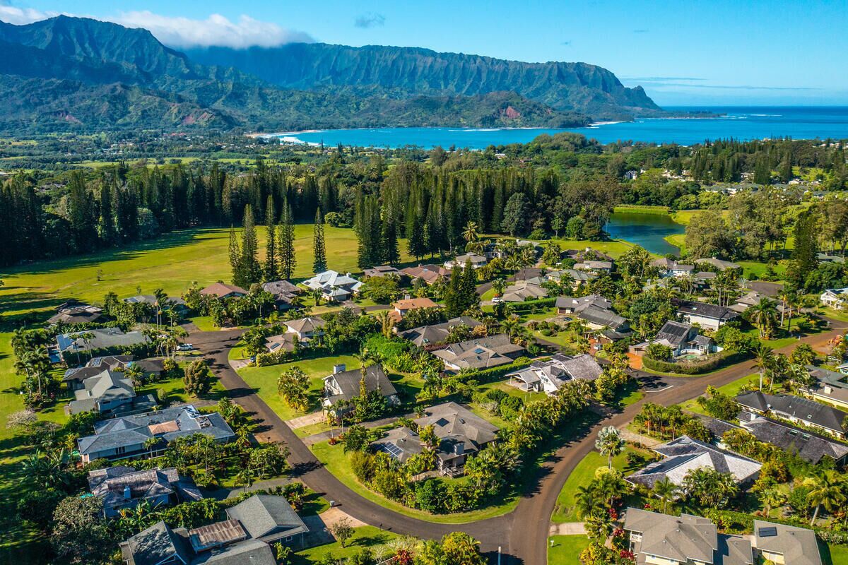 An aerial view of a residential area with houses, roads, and a large body of water in the background.