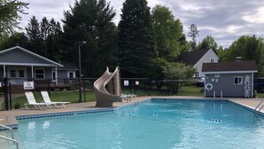 Une piscine avec un toboggan, des chaises longues et un poste de surveillance pour les sauveteurs.