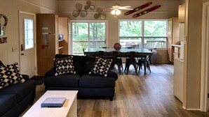 Un salon spacieux avec un canapé de couleur sombre, une table à manger et un ventilateur de plafond.