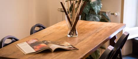 A wooden dining table with a magazine and a glass vase with chopsticks.