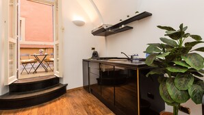 A compact kitchen with a built-in stove, a small dining area with a table and chairs, and a potted plant. - Lovely New home, via Nazionale . (Roma)