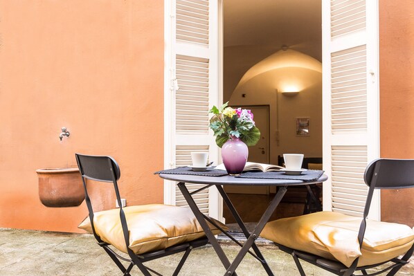 An outdoor seating area with a round table, two chairs, a potted plant, and a book. - Lovely New home, via Nazionale . (Roma)