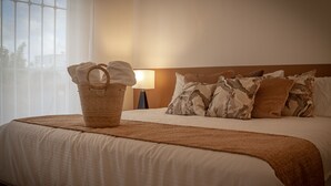 Een net opgemaakt bed met een bruine deken, een mand met een handdoek en gestreepte kussens.