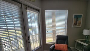 A room with a black leather chair, a small table with a lamp, and a window with blinds. - RECENTLY REMODELED "The Surf Shack" 1st Floor, Overlooks Pond, Close to Beach (Corpus Christi)