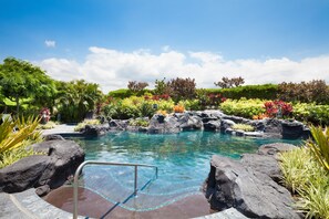 A clear pool surrounded by tropical plants and rocks.