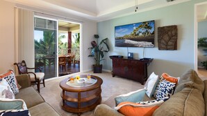 Ein geräumiges Wohnzimmer mit einer großen Schiebeglasdoor zum Balkon, einem runden Holztisch, einer dunklen Holzkommode und einem flachbildfernseher an der Wand.