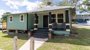 A small, single-story house with a porch and steps leading to the front door. - Pet friendly 1bd/1b unit with living space and full kitchen (Gainesville)