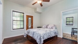 A bedroom with a bed, wooden flooring, a ceiling fan, and two windows with blinds. - Pet friendly 1bd/1b unit with living space and full kitchen (Gainesville)