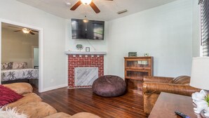 A living room with a fireplace, a ceiling fan, and a television. - Pet friendly 1bd/1b unit with living space and full kitchen (Gainesville)