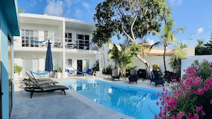 A modern hotel with a pool, outdoor seating, and lush landscaping. - AQUA GUESTHOUSE 3~ STEPS FROM THE BEACH ~ POOL ~ A+ INTERNET (Puerto Morelos,)