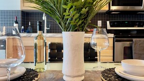 A modern kitchen with a central island featuring a vase of flowers, a wine glass, and a bottle of wine.