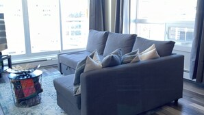 A modern living room with a grey sofa, a patterned rug, and a small side table.