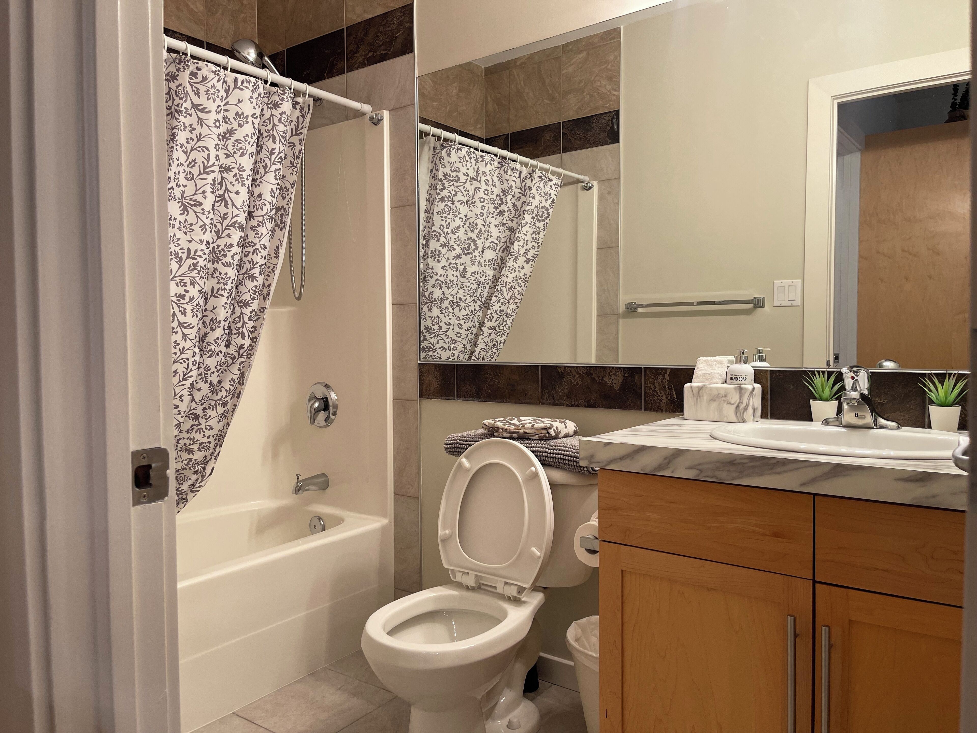 Un baño con bañera, inodoro y tocador con espejo.