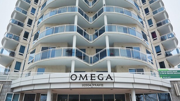 A multi-story building with a curved facade, balconies, and a sign reading "OMEGA" at the ground level.