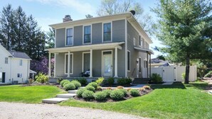 A two-story house with a front porch, a driveway, and a well-maintained lawn. - Alex`s Pool House Private Pool & Hot Tub Centrally Located in the Saugatuck Douglas Area (Douglas)