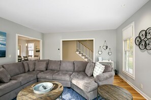 A living room with a gray sectional sofa, a wooden coffee table, and a staircase leading to another level.