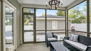 A covered porch with wicker furniture, a chandelier, and large windows. - Alex`s Pool House Private Pool & Hot Tub Centrally Located in the Saugatuck Douglas Area (Douglas)