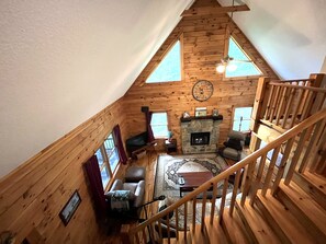 Acogedor loft con chimenea de piedra, vigas de madera en el techo y un reloj grande.