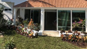 Una casa moderna de dos pisos con techo de tejas, ventanas amplias y un porche cubierto.