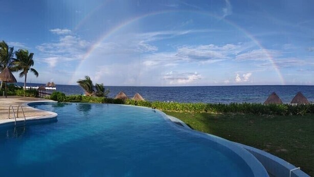 Una piscina con vista al océano y un arcoíris.