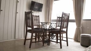 A room with a wooden table and chairs, a television mounted on the wall, and a window with curtains. - ELEGANT 1BED APARTMENT 50 METRES FROM PLAYA DE LOS INGLESES (Punta del Este)