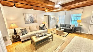 A living room with a wooden ceiling, a ceiling fan, a sofa set, a coffee table, and a rug.