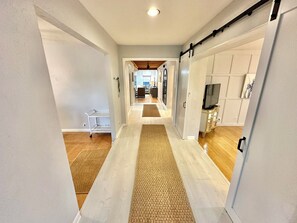 A hallway with a central rug, a sliding door, and a TV stand with a flat-screen TV. - Spacious Resort Home near the Beach Sleeps 18  24SE (Miramar Beach)