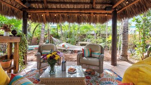 A covered outdoor seating area with wicker furniture, a glass table, and a hammock. - Relaxing 1 Bedroom Garden Apartment steps to the Ocean - Best part of the beach! (Hollywood)
