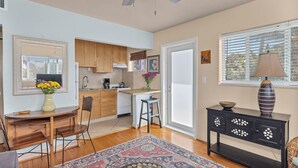 A compact kitchen with wooden cabinets, a dining area with a rug, and a black console table with decorative items. - Relaxing 1 Bedroom Garden Apartment steps to the Ocean - Best part of the beach! (Hollywood)