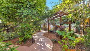 A garden pathway with a pergola structure, surrounded by various plants and trees. - Relaxing 1 Bedroom Garden Apartment steps to the Ocean - Best part of the beach! (Hollywood)