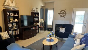 A living room with a television, bookshelf, and a fireplace. - Ione Captains Cottage With 3 separate BEDROOMS Close to Town. Centrally located. (Ione)
