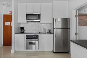 Una cocina moderna con electrodomésticos de acero inoxidable, armarios blancos y salpicadero de azulejos.