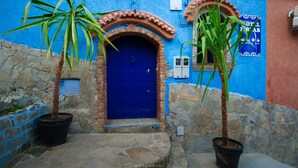 A blue door with a brick archway, potted plants, and a sign indicating a hotel. - Hotel Ziryab (Chefchaouen)