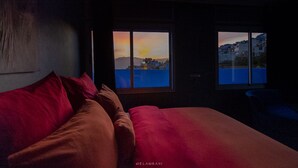 A dimly lit room with a bed and two windows. - Hotel Ziryab (Chefchaouen)