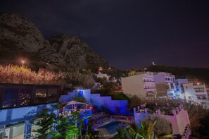 A nighttime view of a coastal town with buildings, a pool area, and a mountain backdrop. - Hotel Ziryab (Chefchaouen)