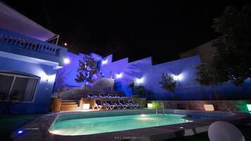 Ein Schwimmbecken mit Liegestühlen und einer Treppe zu einer Terrasse.