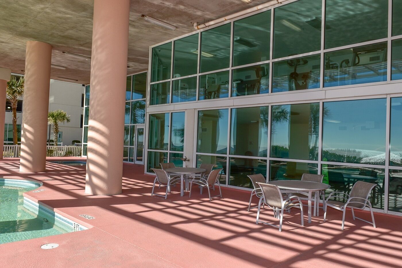 An outdoor pool area with sunlit seating and large windows.