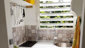 A compact kitchen with a window, a sink, and wooden cabinets.