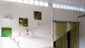 A room with a dining table, chairs, a vase with branches, and wall-mounted shelves with decorative items.