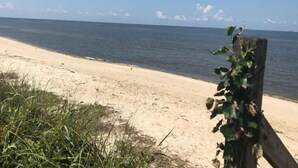 A beach with a wooden post and some vegetation. - Bungalow by the Bay (Villas)
