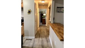 A hallway with a wooden floor, a kitchen area with a wooden countertop, and a sign on the wall. - Bungalow by the Bay (Villas)